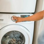 human turning on a laundry machin