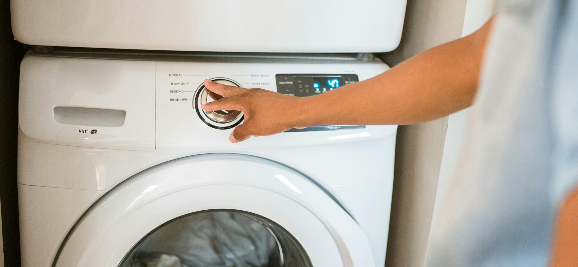 human turning on a laundry machin