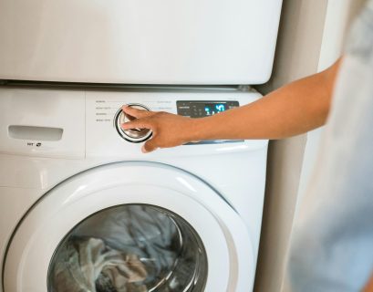 human turning on a laundry machin