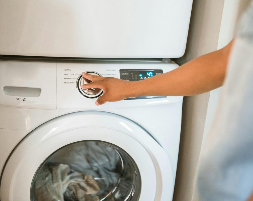human turning on a laundry machin
